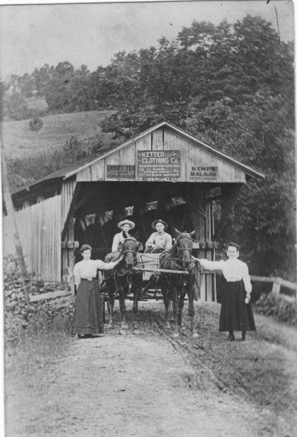 This is the end of the Waterloo bridge closest to Waterloo. Covered bridge ends were popular places to put signs, posters, and ads.  Photo taken in 1909. L-R: Eva Goff, Charles Weatherford, Jr., W.W. Phillips and Stella Marshall Photo courtesy of Mark Howell